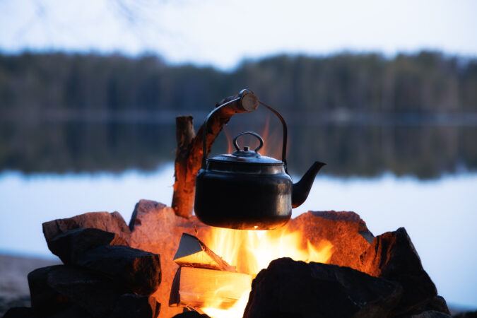 Vintage coffee pot on camping fire. Wonderful evening atmospheri