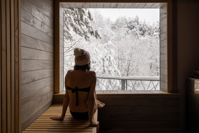 Woman resting in sauna with view on snowy nature