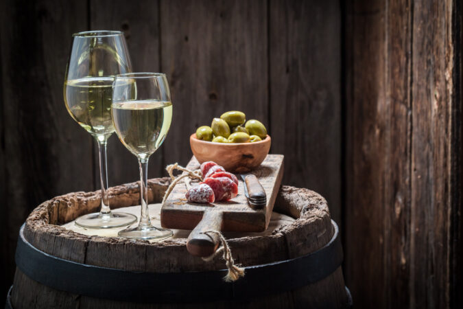 Chardonnay wine with olives and cold cuts on old barrel
